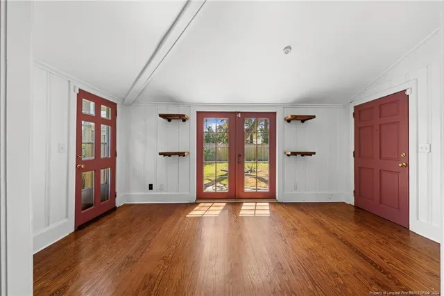 a view of a kitchen and an empty room with wooden floor