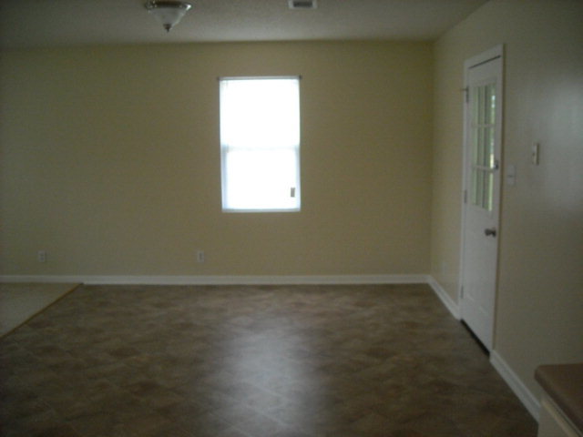 5899 Mt Pleasant Church Road Macon, GA 31216 - Photo 3 of 11 an empty room with wooden floor and windows with curtains