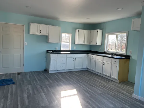 a kitchen with granite countertop a sink cabinets and wooden floor