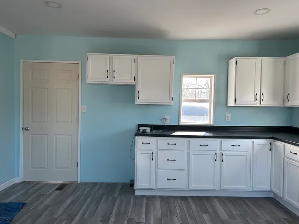 a kitchen with granite countertop white cabinets and a sink