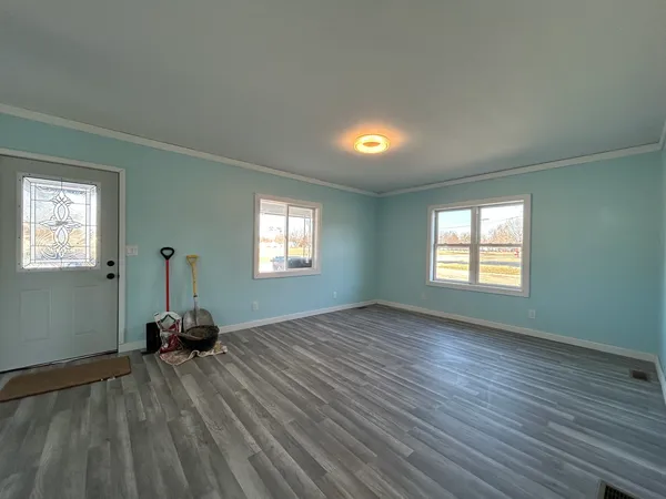 an empty room with wooden floor and windows