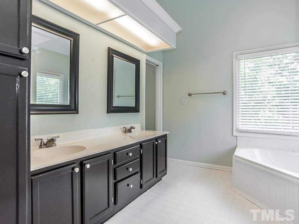3608 Willow Bluff Drive Raleigh, NC 27604 - Photo 20 of 29 a bathroom with a double vanity sink a large mirror a bathtub and window