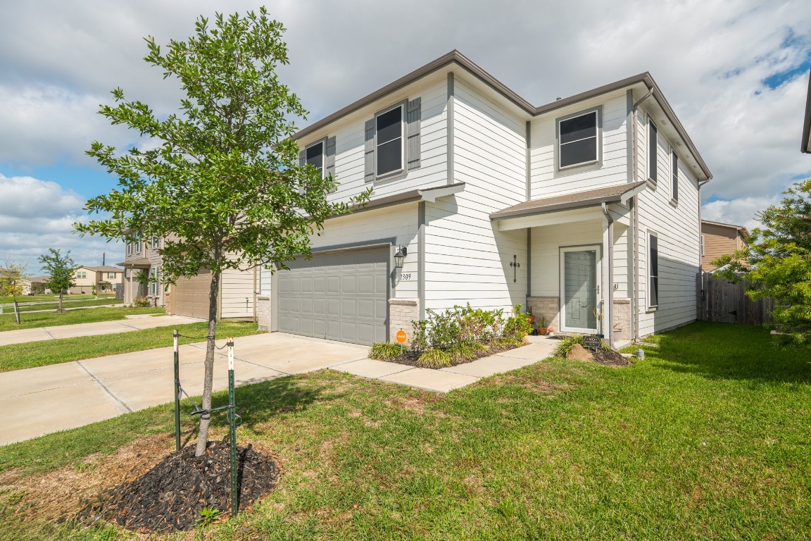 a view of a white house with a yard and large tree