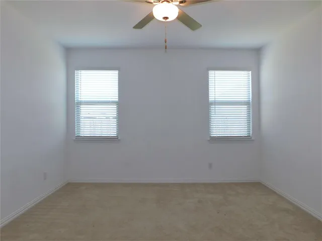 an empty room with a window and a ceiling fan
