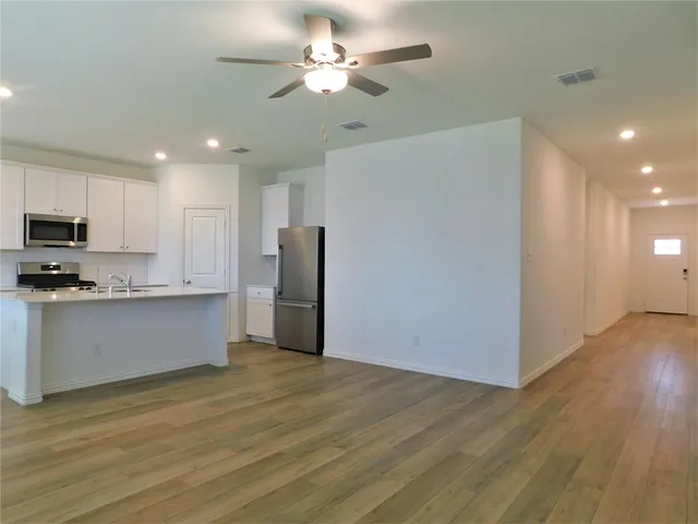 a view of kitchen with stainless steel appliances refrigerator stove microwave and cabinets