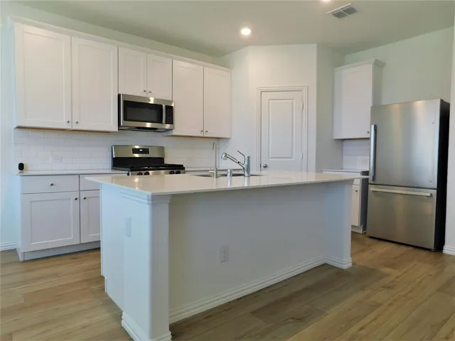 a kitchen with stainless steel appliances white cabinets and a refrigerator