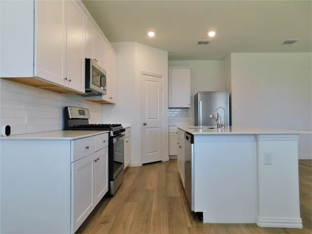 a kitchen with cabinets and wooden floor