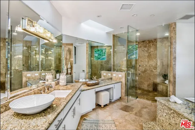 a bathroom with a granite countertop sink a mirror a bathtub and shower
