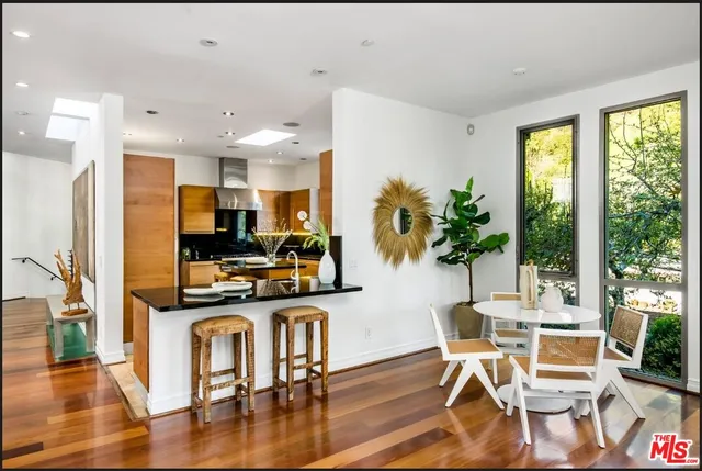 a kitchen with stainless steel appliances granite countertop a stove top oven a refrigerator a dining table and chairs with wooden floor