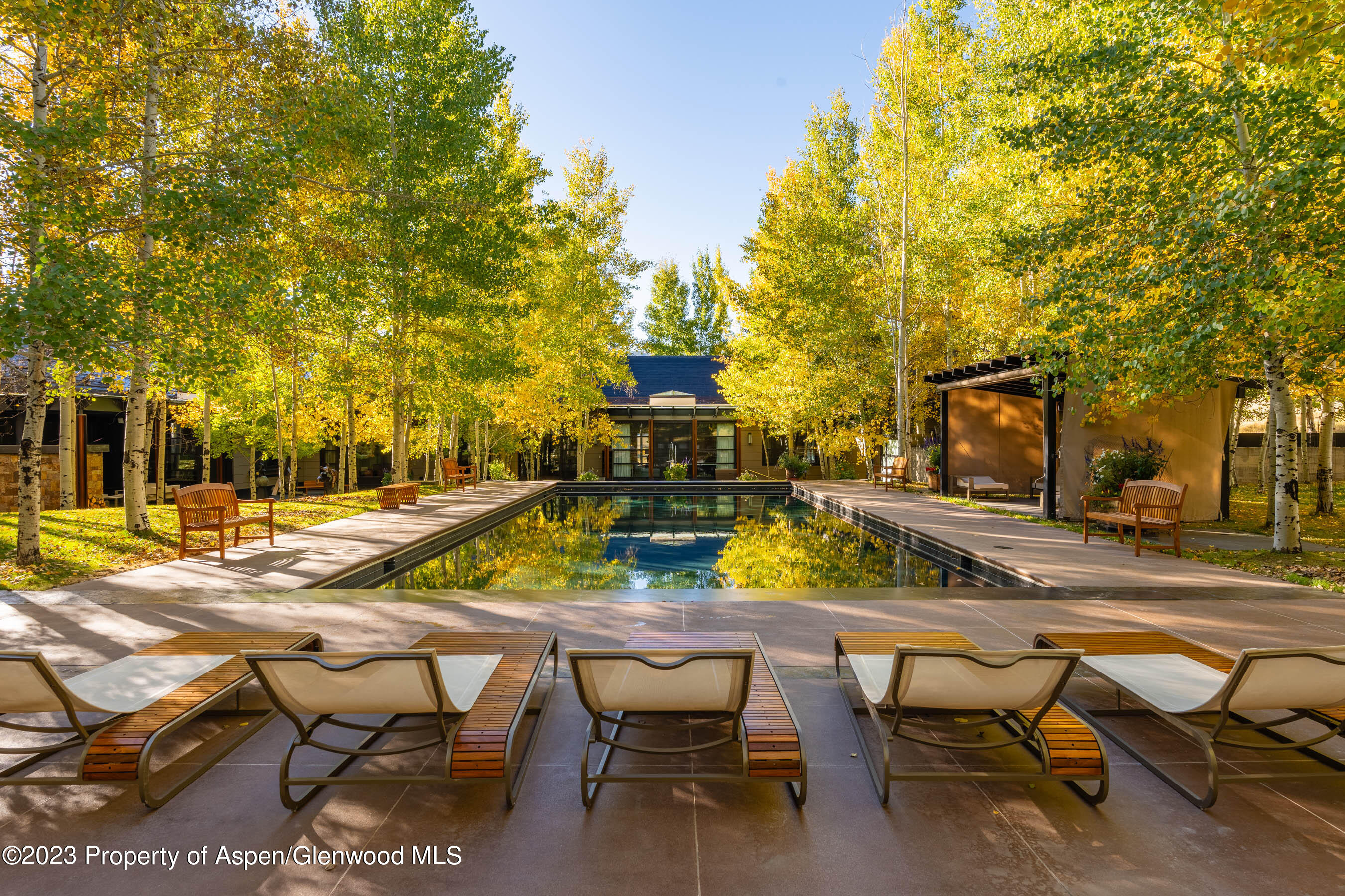 600 Owl Creek Ranch Road Aspen, CO 81611 - Photo 14 of 84 a view of a swimming pool with lawn chairs under an umbrella