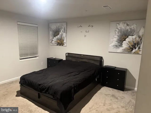 a bedroom with a bed window and painting on the wall