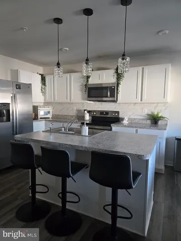 a kitchen with stainless steel appliances granite countertop a sink a stove a refrigerator and chairs