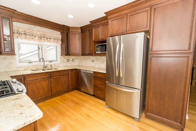 a kitchen with stainless steel appliances granite countertop a refrigerator sink and wooden cabinets