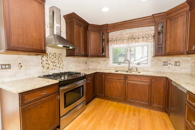 a kitchen with stainless steel appliances granite countertop wooden cabinets sink and stove top oven
