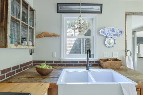 a large white kitchen with a large window appliances and cabinets