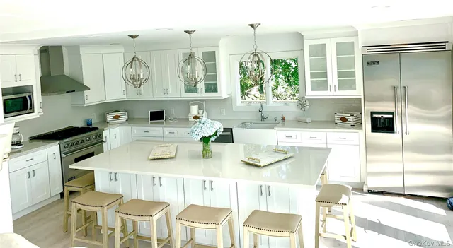 a kitchen with stainless steel appliances kitchen island granite countertop a table chairs and a refrigerator