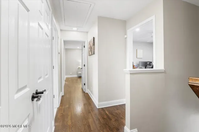 a view of a hallway with wooden floor and a bathroom