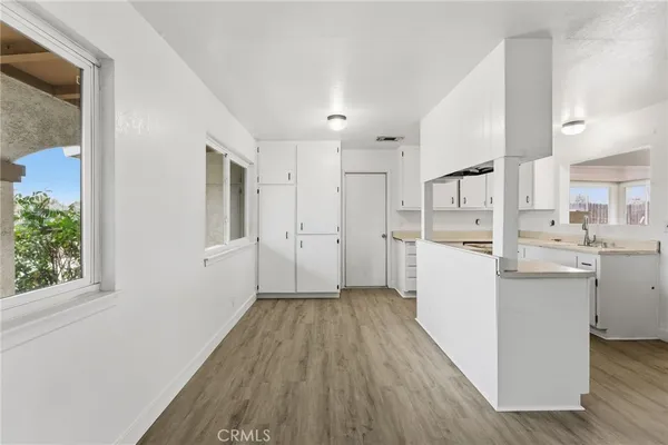 a view of a kitchen with white cabinets stainless steel appliances and window