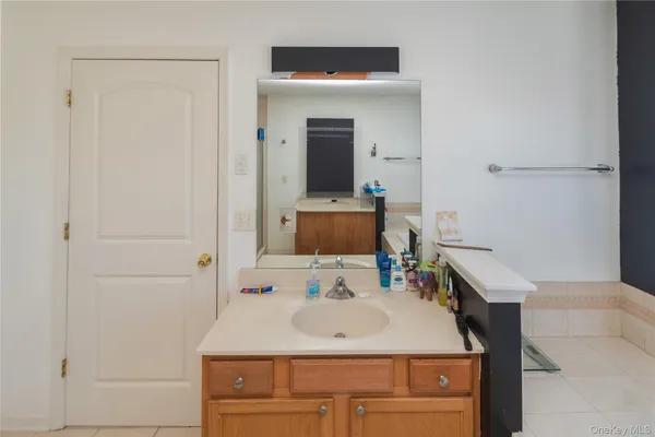 a bathroom with a sink vanity granite tub shower and a mirror