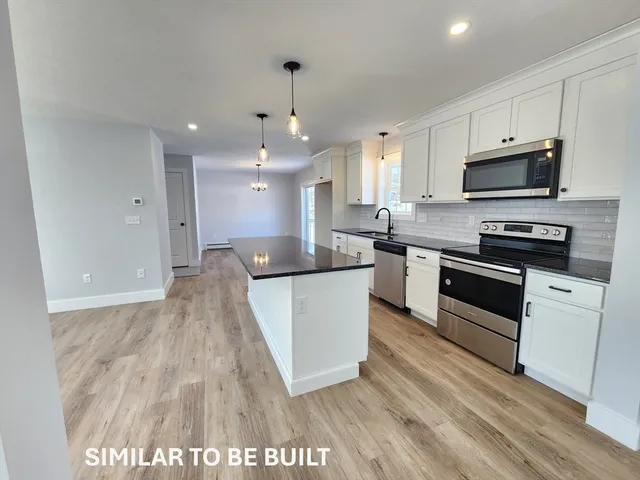 a large kitchen with stainless steel appliances granite countertop a stove a sink and a microwave