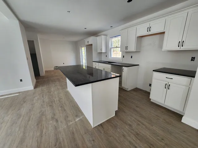 a kitchen with kitchen island a sink a stove a refrigerator and white cabinets