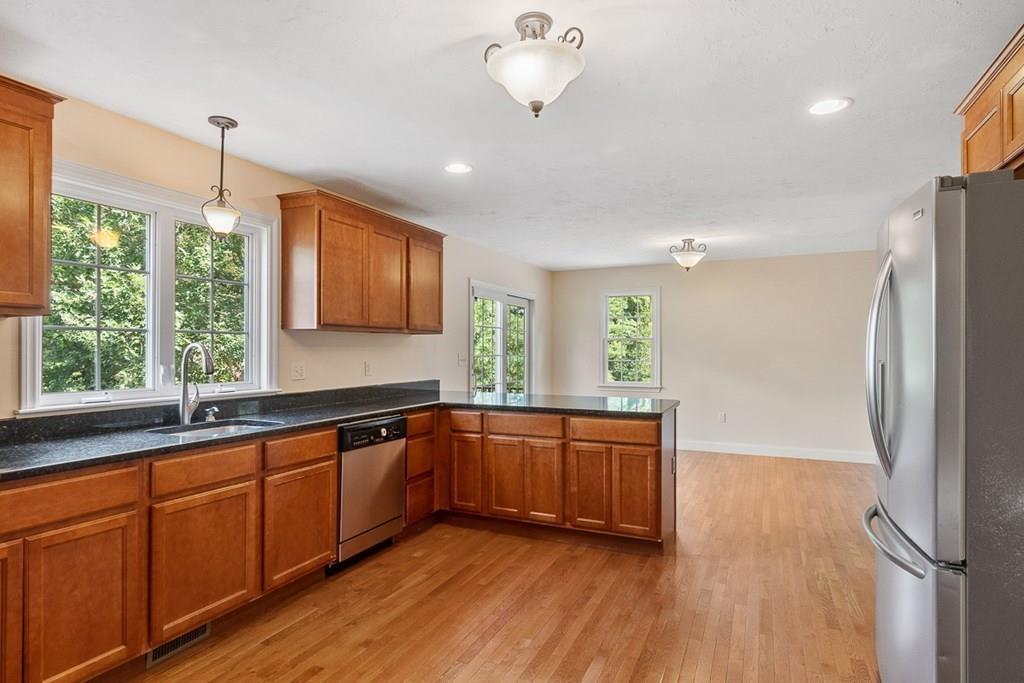 318 Great Road Shirley, MA 01464 - Photo 5 of 36 a kitchen with stainless steel appliances granite countertop a refrigerator a sink dishwasher a stove and white countertops with wooden floor
