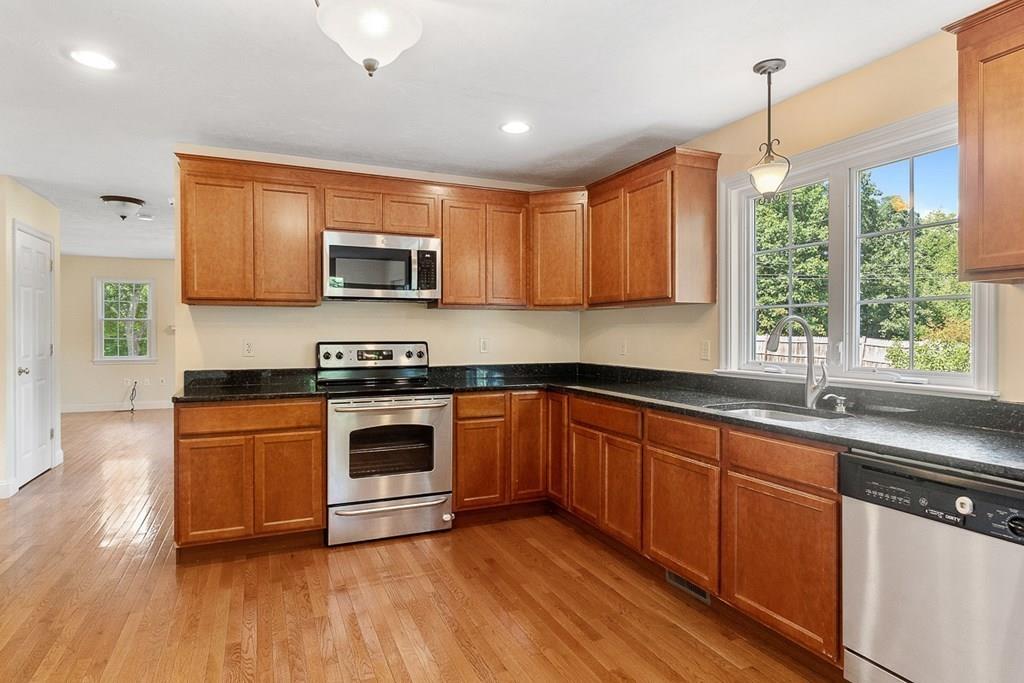 318 Great Road Shirley, MA 01464 - Photo 9 of 36 a kitchen with granite countertop wooden floors stainless steel appliances and a window