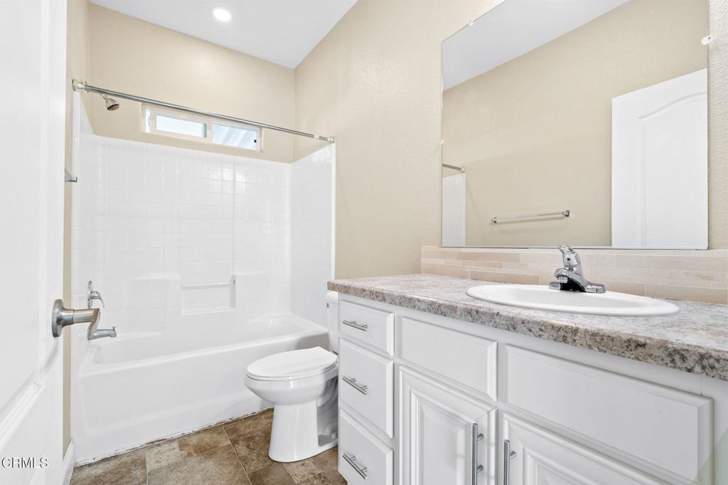 5540 West 5th Street, Unit 1 Oxnard, CA 93035 - Photo 14 of 35 a bathroom with a granite countertop sink toilet mirror and bathtub
