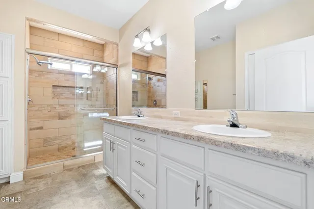 a bathroom with a granite countertop sink a mirror and a shower