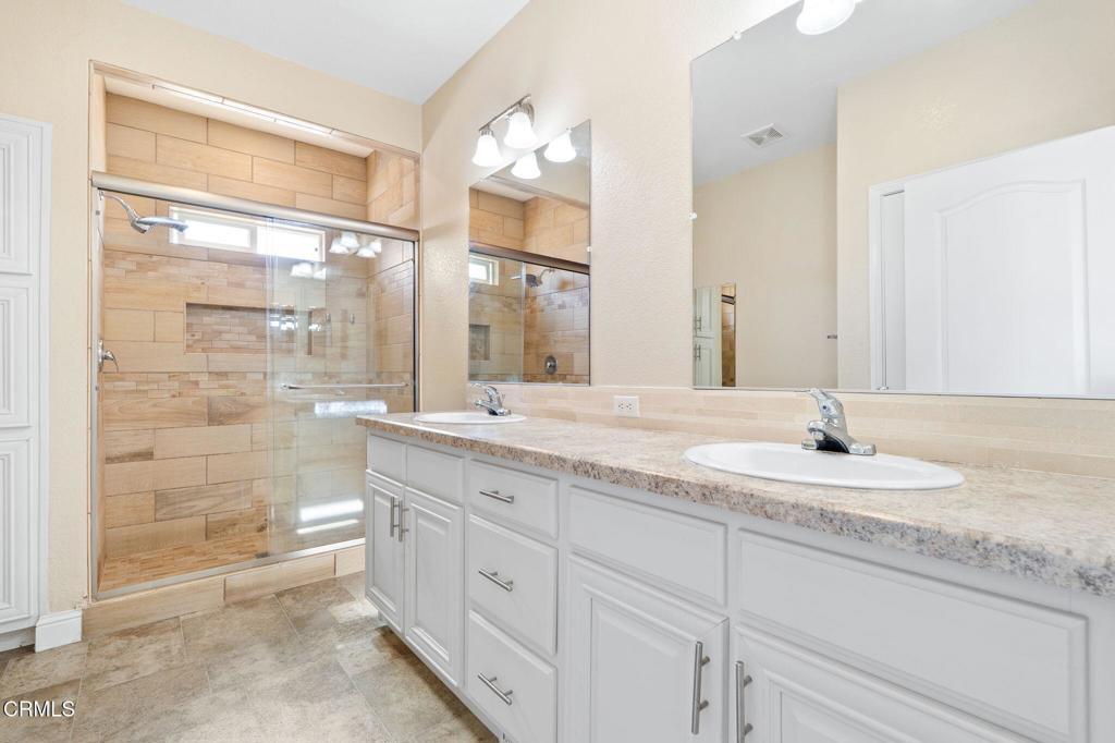 5540 West 5th Street, Unit 1 Oxnard, CA 93035 - Photo 21 of 35 a bathroom with a granite countertop sink a mirror and a shower