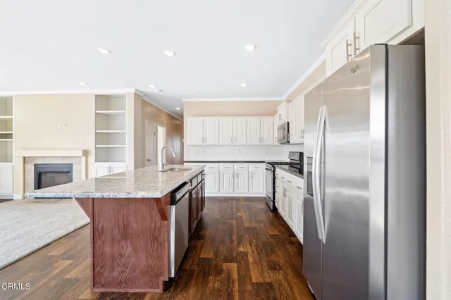 a kitchen with granite countertop a refrigerator a sink a stove and oven with wooden floor