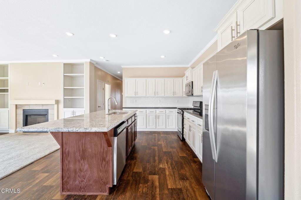 5540 West 5th Street, Unit 1 Oxnard, CA 93035 - Photo 10 of 35 a kitchen with granite countertop a refrigerator a sink a stove and oven with wooden floor