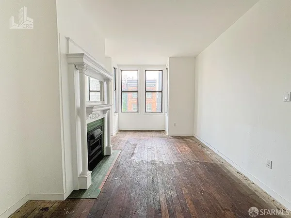 a view of empty room with wooden floor and fireplace