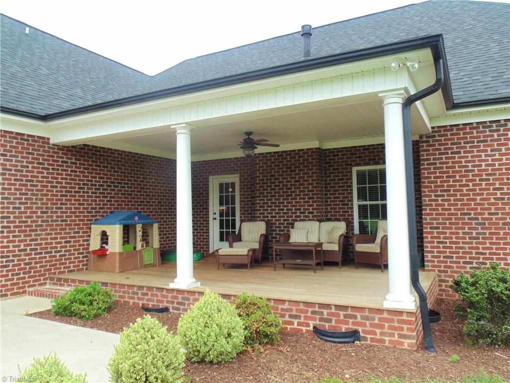 8192 Rylan Drive Browns Summit, NC 27214 - Photo 19 of 21 The covered porch is a beautiful spot to enjoy the peaceful view of the backyard!