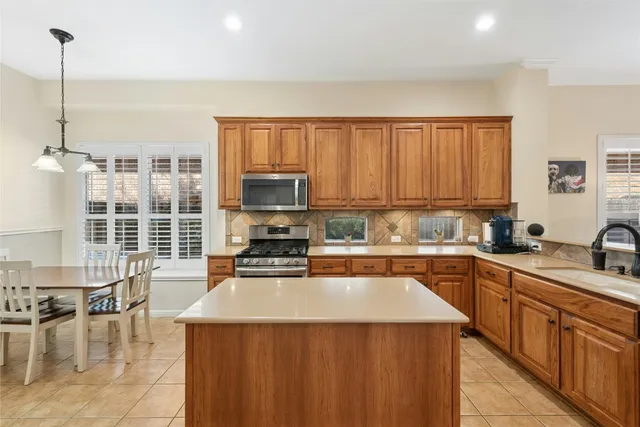 a kitchen with stainless steel appliances a stove a sink a refrigerator a center island and furniture