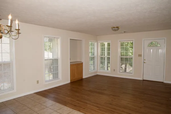 a view of an empty room with wooden floor and a window