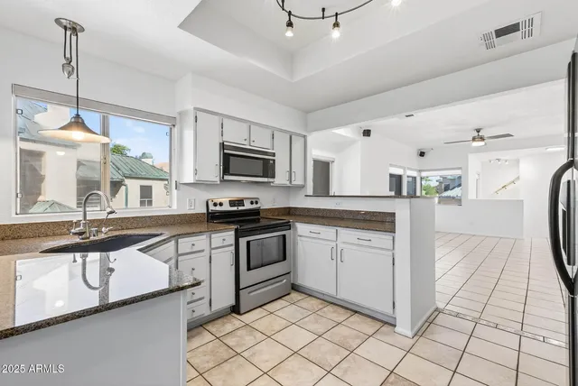 a kitchen with stainless steel appliances granite countertop a refrigerator a sink and white cabinets