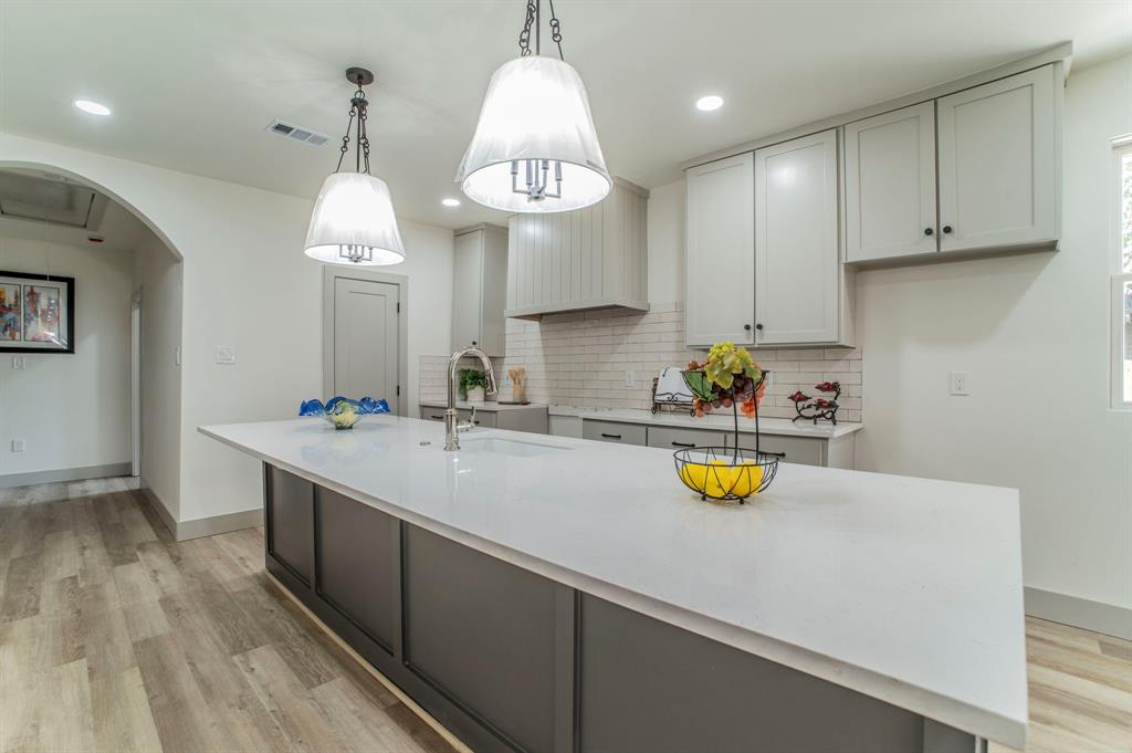 5914 Victor Street Dallas, TX 75214 - Photo 8 of 32 a kitchen with a sink dishwasher a stove and a dining table with wooden floor