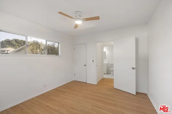 a view of empty room with wooden floor and fan
