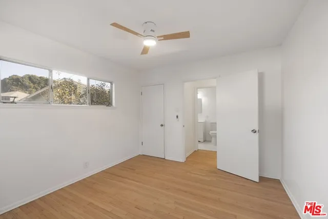 a view of empty room with wooden floor and fan