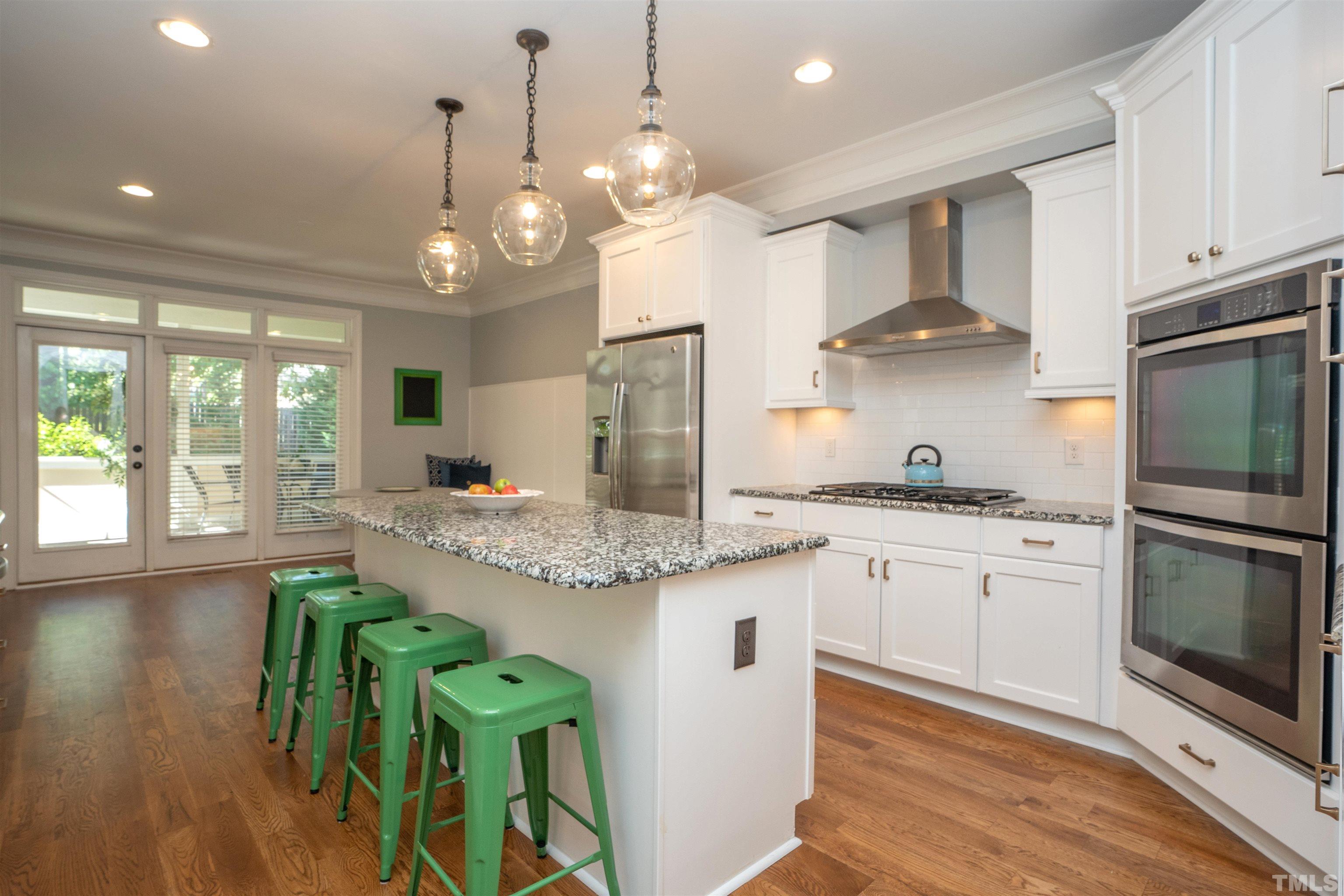 232 Bayleaf Drive Raleigh, NC 27615 - Photo 9 of 26 a kitchen with stainless steel appliances granite countertop a stove a sink a refrigerator and a dining table with wooden floor
