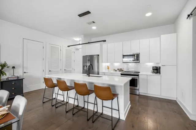 a kitchen with stainless steel appliances a white table and chairs in it