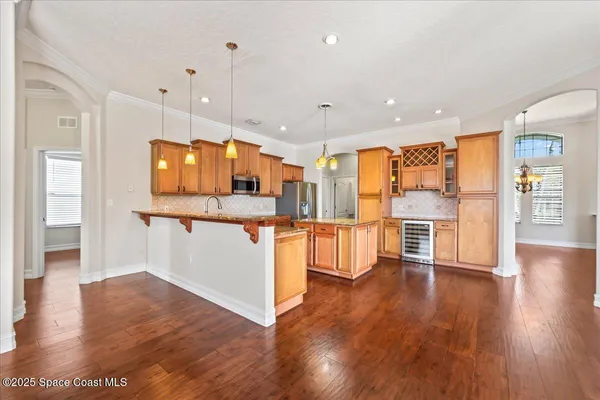 a kitchen with stainless steel appliances granite countertop a refrigerator a sink dishwasher a stove and white countertops with wooden floor