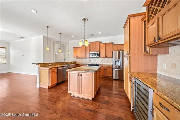 a kitchen with stainless steel appliances granite countertop a stove a sink and a granite counter tops with white cabinets next to a window
