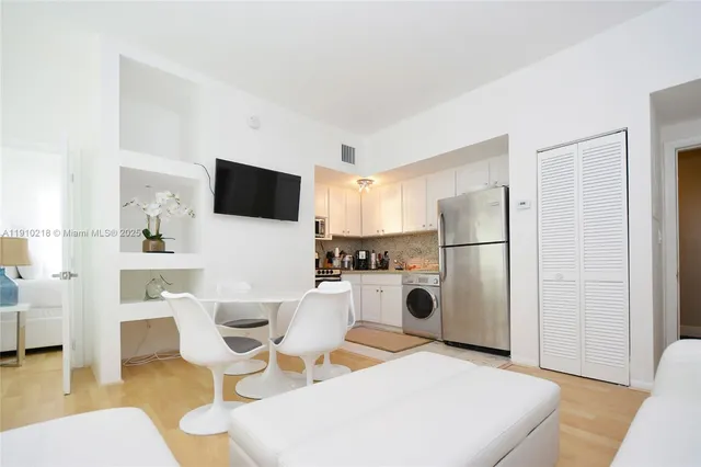 a living room with furniture a refrigerator and a dining table with wooden floor