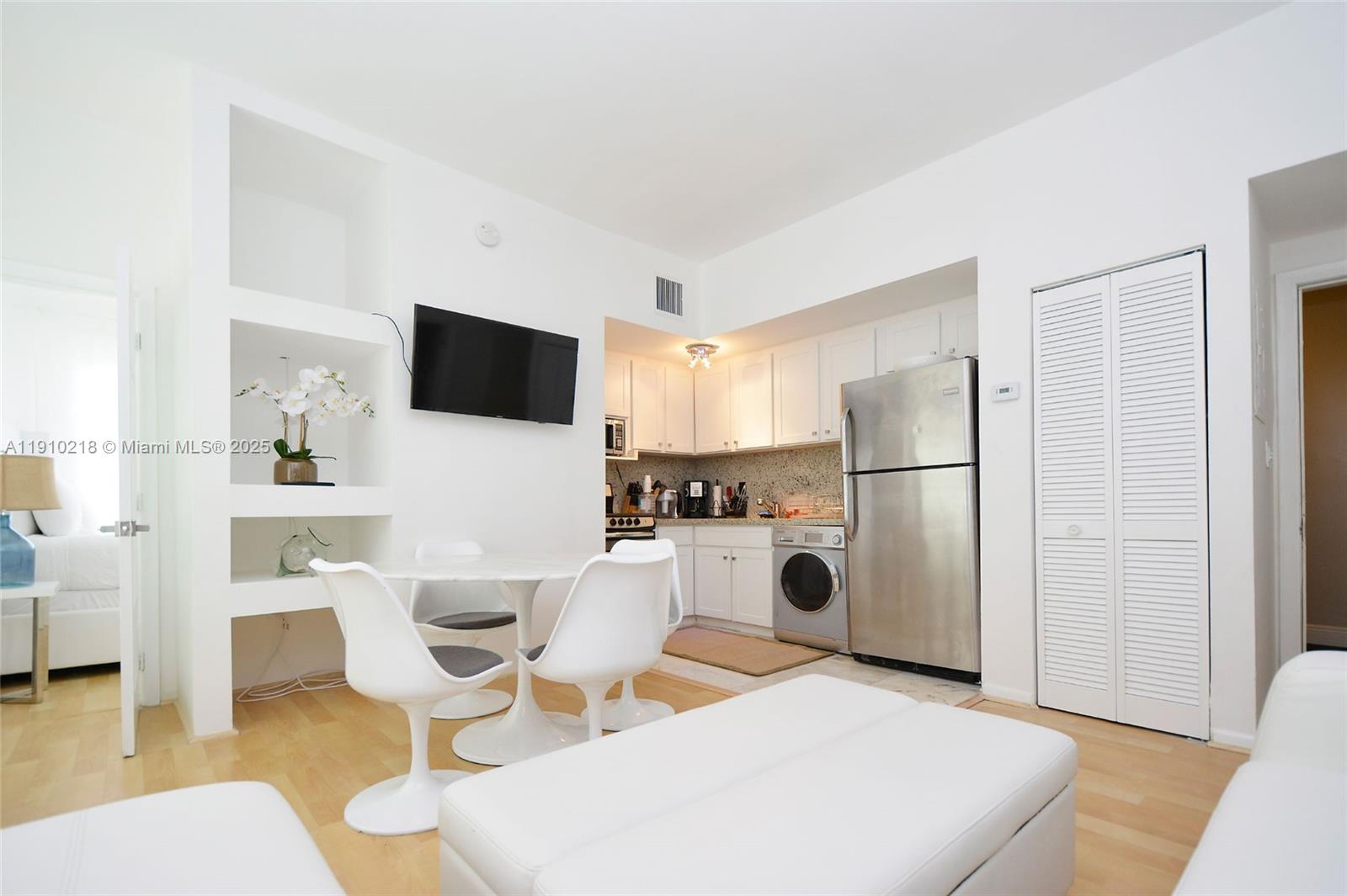 1342 Drexel Avenue, Unit 105 Miami Beach, FL 33139 - Photo 6 of 12 a living room with furniture a refrigerator and a dining table with wooden floor