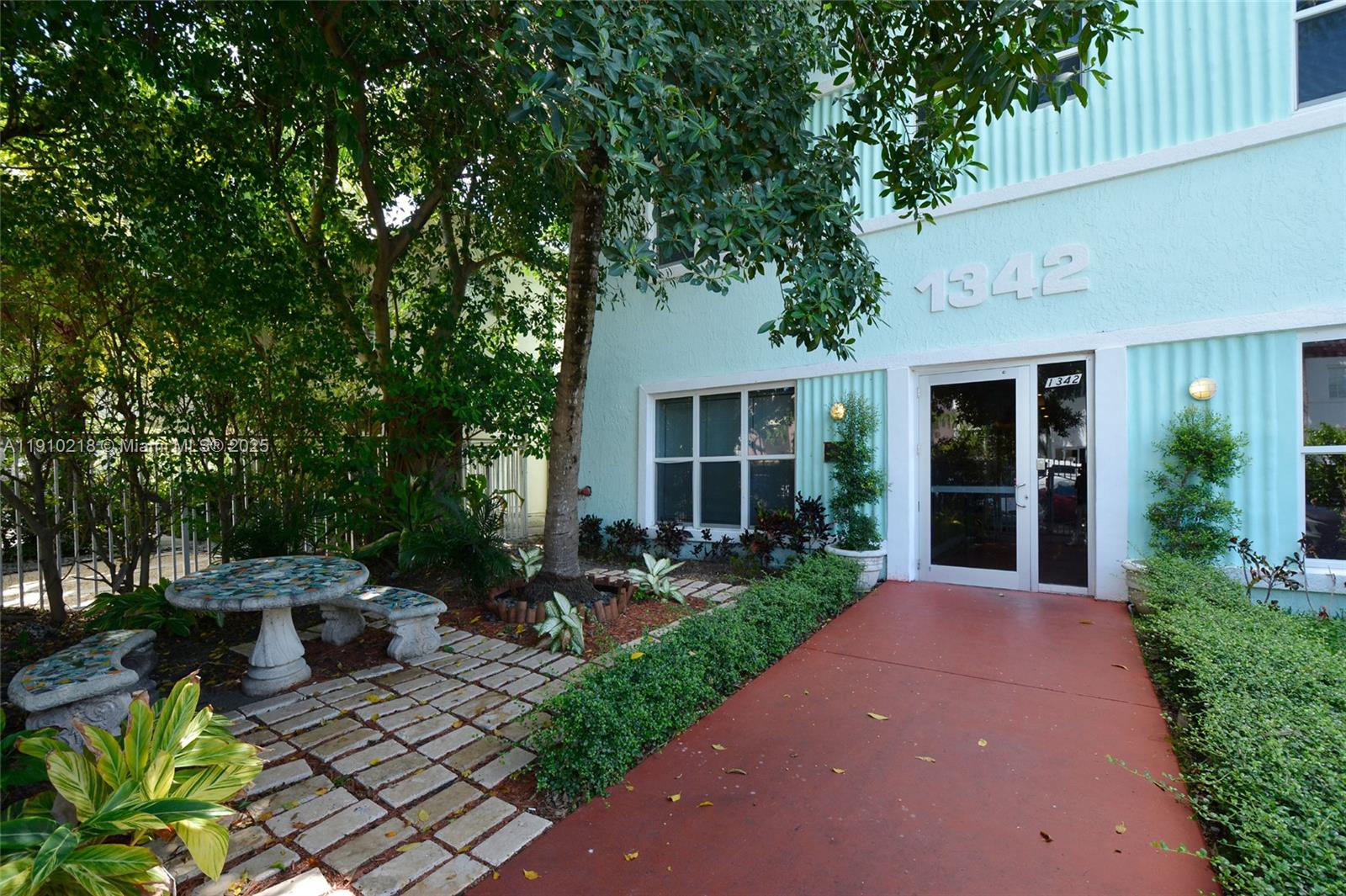 1342 Drexel Avenue, Unit 105 Miami Beach, FL 33139 - Photo 10 of 12 a view of a patio with couches table and chairs potted plants and large tree