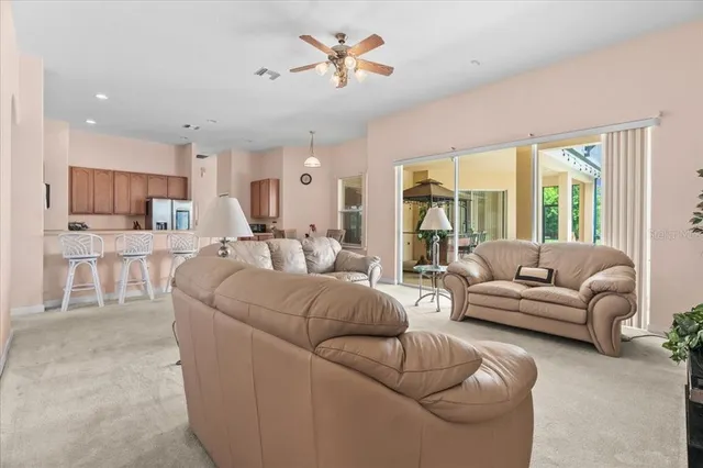 a living room with furniture and a large window with kitchen view