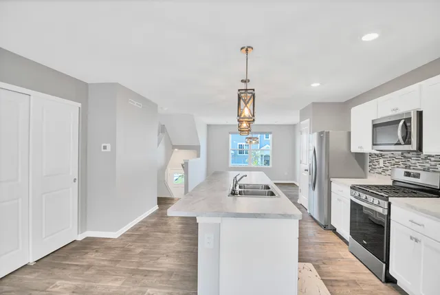 a kitchen with stainless steel appliances granite countertop a sink a stove and a refrigerator