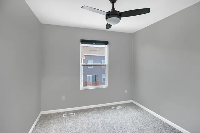 an empty room with a window and a fan